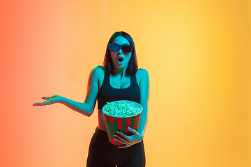 Image showing Young woman\'s portrait on yellow-orange studio background in neon light