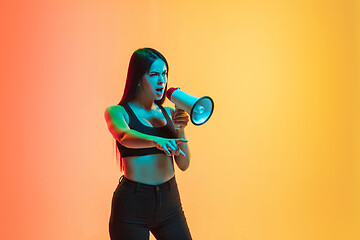 Image showing Young woman\'s portrait on yellow-orange studio background in neon light