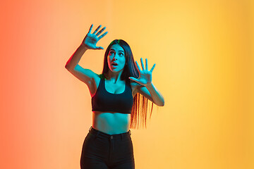 Image showing Young woman\'s portrait on yellow-orange studio background in neon light