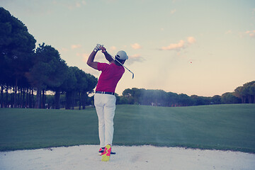 Image showing golfer hitting a sand bunker shot on sunset