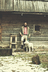 Image showing hipster with dog in front of wooden house