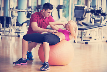 Image showing young sporty woman with trainer exercise in fitness gym