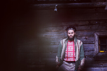 Image showing portrait of young hipster in front of wooden house