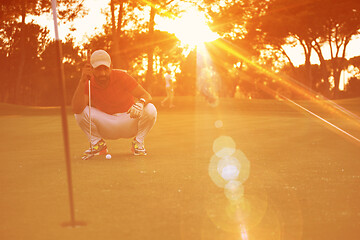 Image showing golf player aiming perfect  shot on beautiful sunset