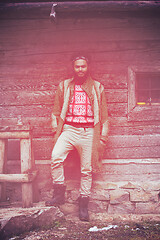 Image showing portrait of young hipster in front of wooden house