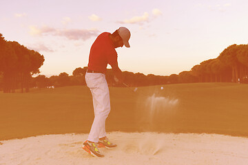 Image showing golfer hitting a sand bunker shot on sunset