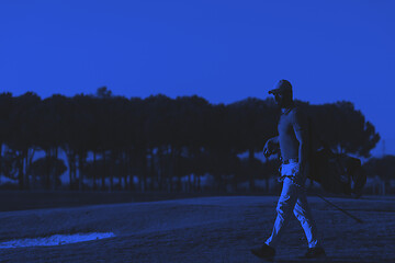 Image showing golfer  walking and carrying golf  bag at beautiful sunset