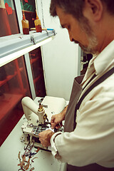 Image showing Sewing process of the leather belt. old Man\'s hands behind sewing.