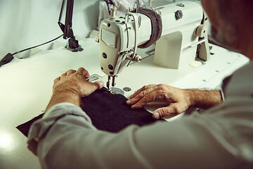 Image showing Sewing process of the leather belt. old Man\'s hands behind sewing.