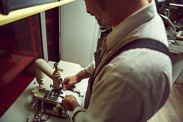 Image showing Sewing process of the leather belt. old Man\'s hands behind sewing.