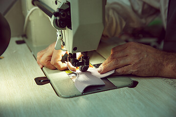 Image showing Sewing process of the leather belt. old Man\'s hands behind sewing.