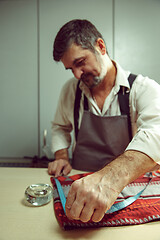 Image showing Closeup of tailors table with male hands tracing fabric making pattern for clothes