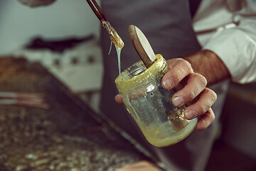 Image showing Shoemaker makes shoes for men.He smears special liquid with a brush.