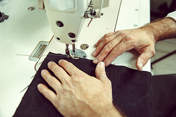 Image showing Sewing process of the leather belt. old Man\'s hands behind sewing.