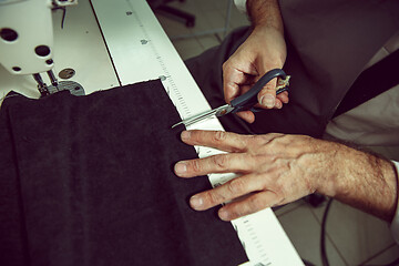 Image showing Sewing process of the leather belt. old Man\'s hands behind sewing.