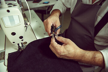 Image showing Sewing process of the leather belt. old Man\'s hands behind sewing.