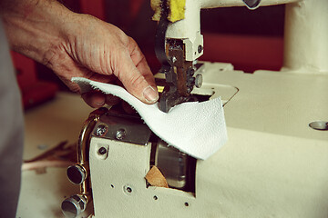 Image showing Sewing process of the leather belt. old Man\'s hands behind sewing.