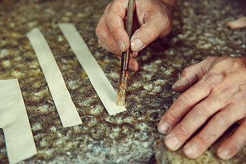 Image showing Shoemaker makes shoes for men.He smears special liquid with a brush.