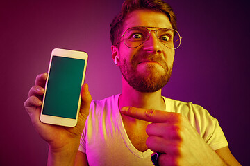 Image showing Indoor portrait of attractive young man holding blank smartphone