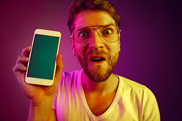 Image showing Indoor portrait of attractive young man holding blank smartphone