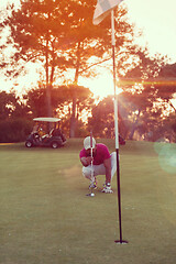 Image showing golf player aiming perfect  shot on beautiful sunset