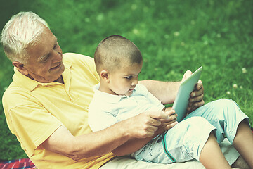 Image showing grandfather and child in park using tablet