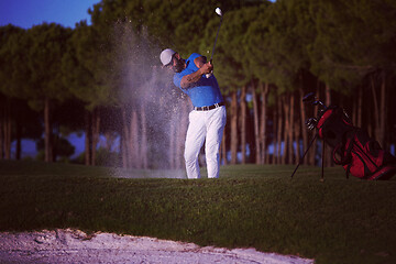 Image showing golfer hitting a sand bunker shot on sunset