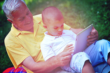 Image showing grandfather and child in park using tablet