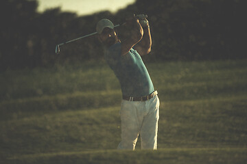 Image showing golfer hitting a sand bunker shot on sunset