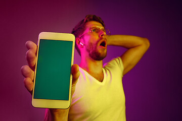 Image showing Indoor portrait of attractive young man holding blank smartphone