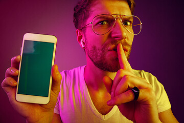 Image showing Indoor portrait of attractive young man holding blank smartphone