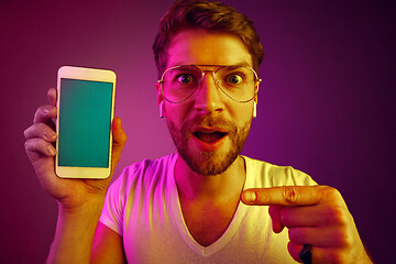 Image showing Indoor portrait of attractive young man holding blank smartphone