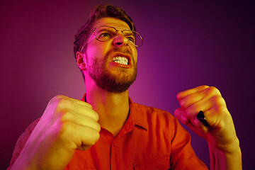 Image showing The young emotional angry man screaming on pink studio background