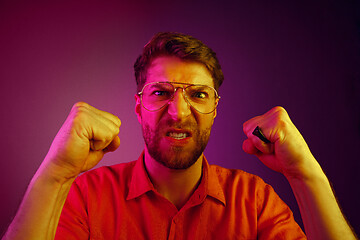 Image showing The young emotional angry man screaming on pink studio background