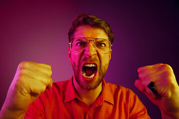 Image showing The young emotional angry man screaming on pink studio background