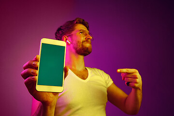 Image showing Indoor portrait of attractive young man holding blank smartphone