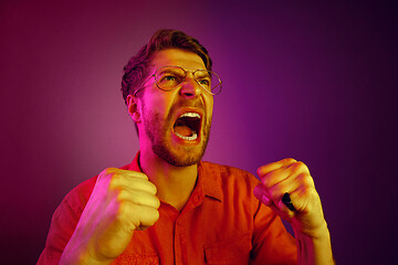 Image showing The young emotional angry man screaming on pink studio background