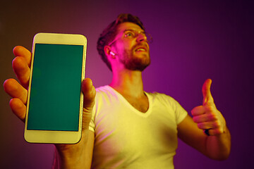 Image showing Indoor portrait of attractive young man holding blank smartphone