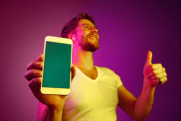 Image showing Indoor portrait of attractive young man holding blank smartphone