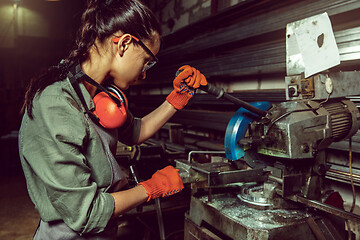 Image showing Busy and serious craftswoman grinding timbers with special machine.