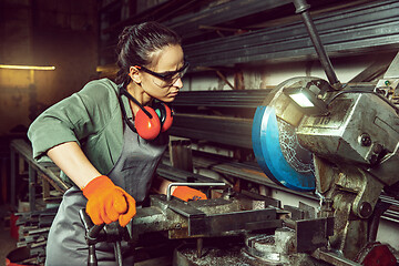 Image showing Busy and serious craftswoman grinding timbers with special machine.