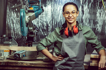 Image showing Smiling craftswoman grinding timbers with special machine.