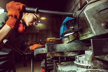 Image showing Busy and serious craftswoman grinding timbers with special machine.