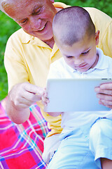 Image showing grandfather and child in park using tablet