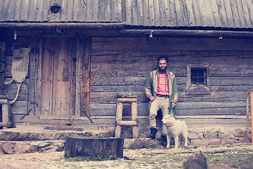 Image showing hipster with dog in front of wooden house