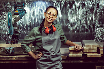 Image showing Smiling craftswoman grinding timbers with special machine.