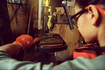 Image showing Busy and serious craftswoman grinding timbers with special machine.