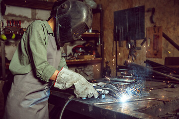 Image showing Busy and serious craftswoman grinding timbers with special machine.