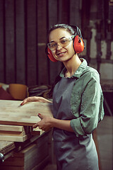 Image showing Smiling craftswoman grinding timbers with special machine.