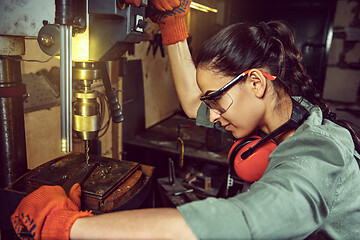 Image showing Busy and serious craftswoman grinding timbers with special machine.